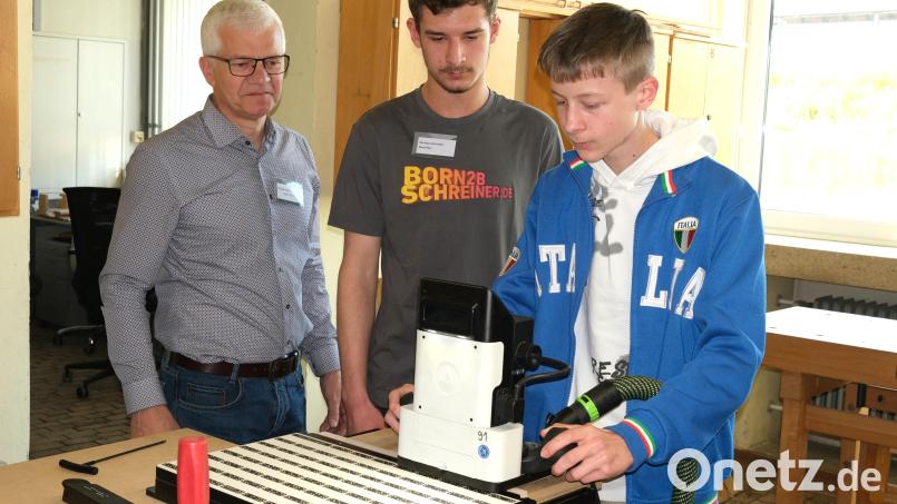 Unter Anleitung von Ausbilder Xaver Wiendl und Berufsschüler Nico Brandl (von links) fräst Fabio Merl (rechts) seinen Namen in das zuvor gefertigte Brotzeitbrettl. Bild: Hirsch
