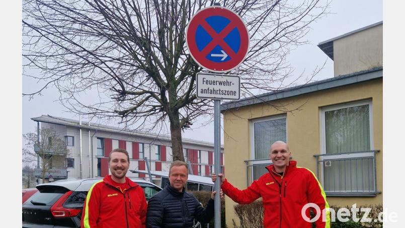 Die Vertreter der DLRG Amberg, Rainer Kratzer (links) und Max Kratzer (rechts) sowie Landtagsabgeordneter Bernhard Heinisch mit dem nun versetzten Schild. Bild: Danny Naber