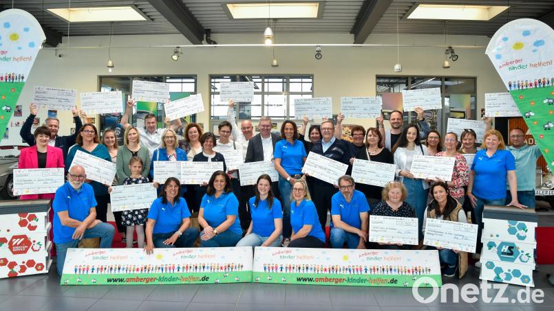 So viele Menschen kommen glücklich lächelnd zusammen – schließlich halten sie alle große Schecks in den Händen –, wenn &quot;Amberger Kinder helfen&quot; seine Spenden verteilt: Diesmal 15.000 Euro an 23 Empfänger, die zur Übergabe in die neue Oldtimer-Galerie der Spedition Wagner eingeladen waren, um thematisch auch gleich Werbung für das Familienevent &quot;Motorwelten&quot; des Vereins zu machen. In der Mitte stehend neben OB Michael Cerny Vorsitzende Anne Wagner (im blauen Polohemd). Bild: Petra Hartl