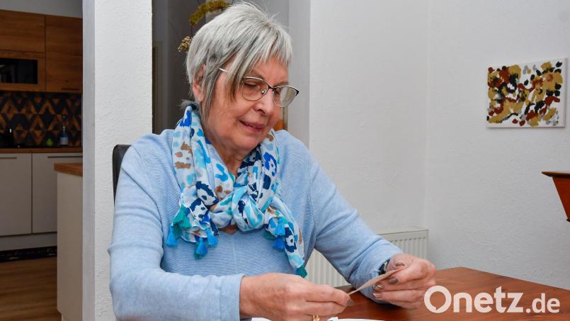 Gaby Wennicke aus Amberg betrachtet alte Fotos, die ihren Vater Hans Kowar und den französischen Geistlichen Henri Cellérier zeigen. Bild: Petra Hartl