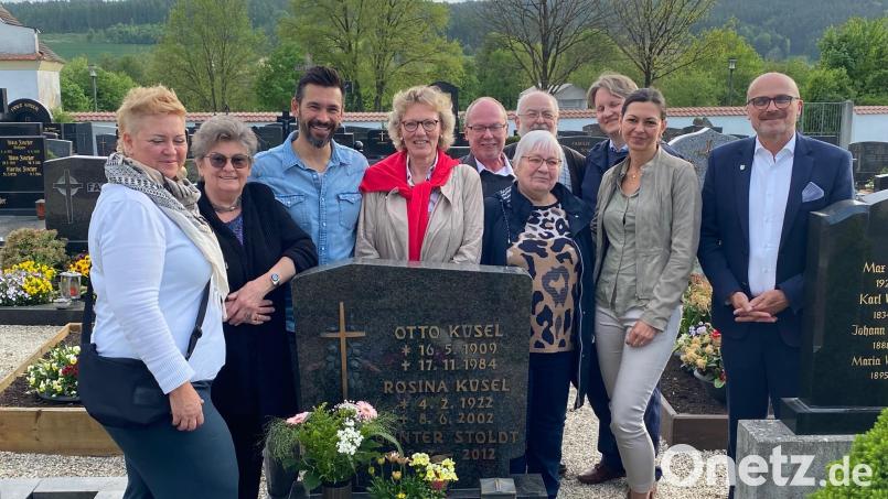 Am Grab des in Schwarzhofen sesshaft gewordenen KZ-Häftlings Nr. 2 von Auschwitz, Otto Küsel, stellte Bürgermeister Maximilian Beer (rechts) mit der Tochter von Otto Küsel, Renate Grün, (Zweite von links) und deren Familienangehörigen sowie Autor Sebastian Christ (hintere Reihe, rechts) und Ortsheimatpfleger Alfred Wolfsteiner (hintere Reihe, Zweiter von rechts) eine Schale ab. Bild: Philipp Ankenbrand