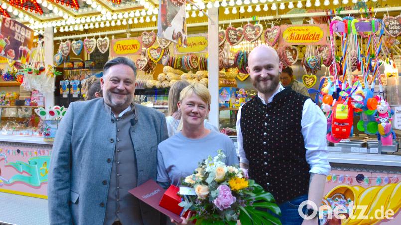 Bürgermeister Thomas Beer gratulierte der Teublitzer Schaustellerin und „Fachfrau für Süßwaren“ Angelika Fischer im Beisein von Volksfest-Organisationsleiter Thomas Stegerer (von links) zum 25. Jubiläum beim Volksfest. Bild: Julia Lösche