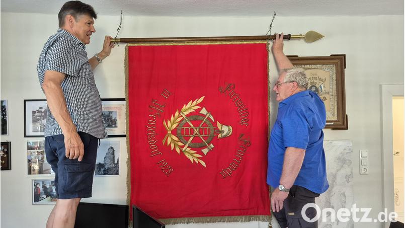 Peter Lampl (links) und Hans Vogl hängen die jetzt in Stadlern beheimatete, 1928 geweihte Fahne der ehemaligen Feuerwehr Wenzelsdorf neben ihrem Gründungsfoto von 1908 auf Bild: eib