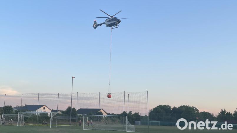 Ein Löschbehälter an einem Helikopter wird auf dem Sportplatz des SC Kreith/Pittersberg von Einsatzkräften befüllt, um den Brand zu bekämpfen. Bild: Lukas Büchold