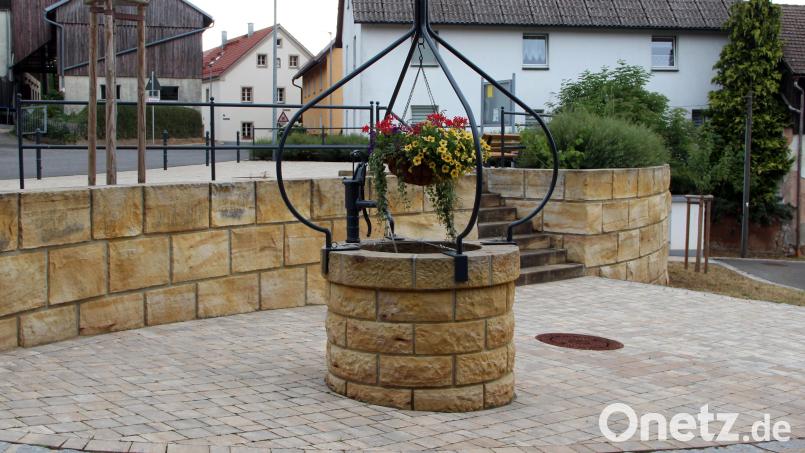 Der Blick fällt auf den hinteren Bereich des Dorfplatzes in der Mitte der Ortschaft. Der wieder aufgebaute Dorfbrunnen erinnert an die gute alte Zeit, wo hier Wasser entnommen werden konnte. Auf diesem Platz steht der Maibaum und in der Weihnachtszeit ein Christbaum. Bild: lep