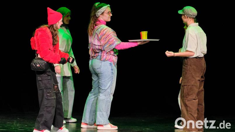 Die Großmutter bietet Passanten Erfrischungsgetränke an, während Red Cap (links) und ihre Freundin Wolfi schon darauf warten, wie die Getränke wirken. Die Luitpold-Mittelschule (Theatergruppe der 7./8. Jahrgangsstufe) hat in &quot;Red Cap&quot; das Märchen von Rotkäppchen umgestülpt – hier bei der Auftaktveranstaltung der Schultheatertage am 21. Februar. Bild: Peter Ringeisen