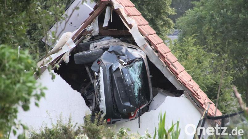 Ein Auto liegt nach einem kurzen Flug seitlich in der Mauer einer Scheune. Bild: -/Moonshine Media/dpa
