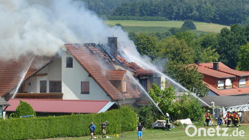 Aus dem Dachstuhl des Wohnhauses quellen dunkle Schwaden, während Feuerwehrleute gegen die Flammen ankämpfen. Bild: lgc