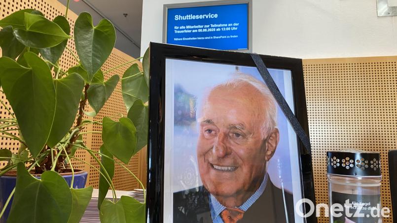 Ein Foto des verstorbenen Ernst Hanauer steht am Empfang des EMZ-Hauptsitzes in Nabburg, im Hintergrund auf dem Bildschirm wird ein Shuttleservice zum Trauergottesdienst für alle Mitarbeitenden angeboten. Bild: Sebastian Böhm