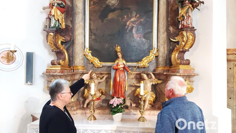 Maria Hummer, hier mit Ehemann Herbert, und deutet auf Details im Nepomuk-Gemälde, wie beispielsweise die Bergung von Nepomuks Leichnam in der Moldau. Bild: lg