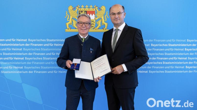 Finanz- und Heimatminister Albert Füracker überreicht das Verdienstkreuz am Bande an Reinhold Wildenauer. Bild: StMFH/Christian Blaschka