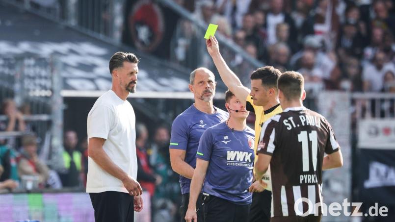 Schiedsrichter Harm Osmers zeigt Trainer Sandro Wagner (FC Augsburg, l) die gelbe Karte. Bild: Christian Charisius/dpa
