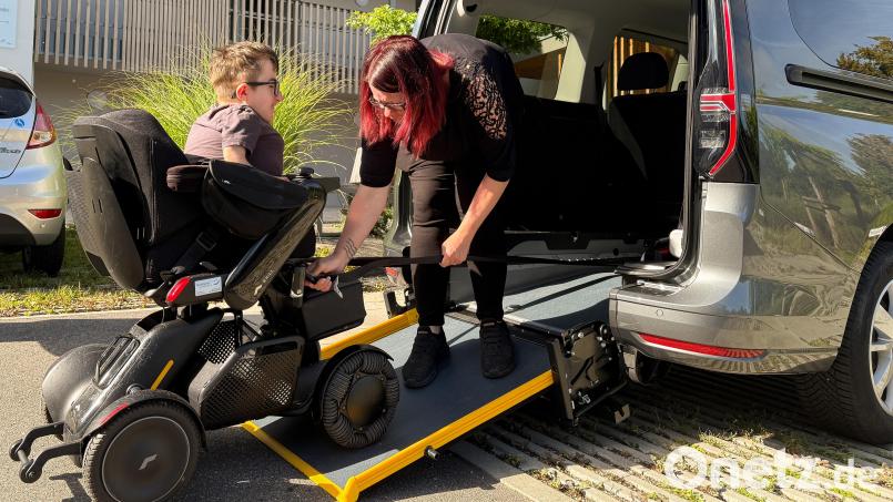 Andrea Lehmeier befestigt die Spanngurte am Rollstuhl ihres Sohnes. Bild: Wolfgang Steinbacher