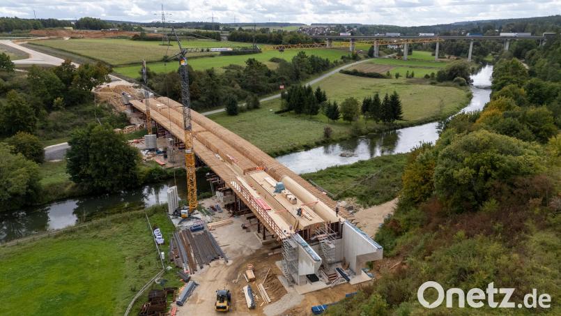 Die neue Vilsbrücke bei Theuern, die größte der acht Brücken der Kümmersbrucker Westumgehung, nimmt Gestalt an. Links hinten im Bild beginnt die Umgehungsstraße nahe der Autobahnauffahrt Amberg-Süd, führt dann über die Brücke und (im rechten unteren Drittel des Bildes) weiter Richtung Grammer/Haselmühl. Bild: hbe