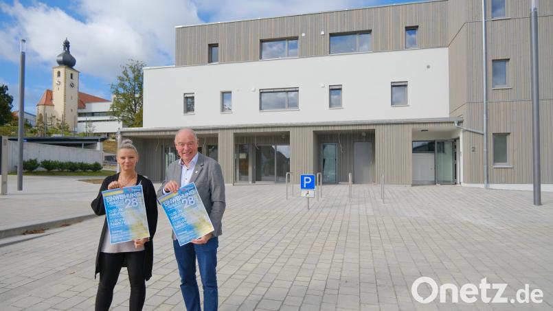 Bürgermeister Roland Strehl und Michaela Mildner auf dem neuen Dorfplatz mit dem Plakat über die Einweihungsfeier. Bild: gsp