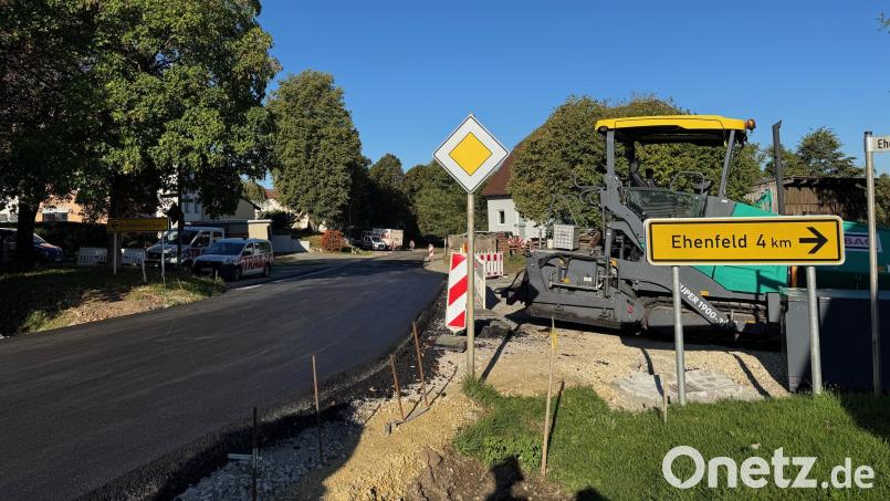 Fast fertig: Die Staatsstraße 2123 wird seit vier Wochen saniert. In Großschönbrunn wurde am Freitag die Asphalt-Deckschicht aufgebracht. An deren derzeit noch rauen Kanten (rechts) sieht man, wieviel höher die Straße geworden ist, weil die neue über die alte gebaut wurde. Bild: Heike Unger