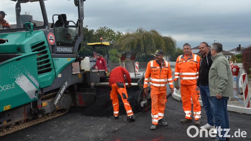 Eine große Asphaltiermaschine trägt den Deckenbau auf den Amselweg auf. Die Arbeiten haben sich wegen wettertechnischen Gründen verzögert, informierte Außendienstleiter Michael Gösl (Zweiter von rechts), der sich mit Bürgermeister Andreas Wutzlhofer (rechts) und den städtischen Mitarbeitern Jörg Fikus und Manfred Bojer (von links) vom Fortschritt überzeugten. Bild: dob