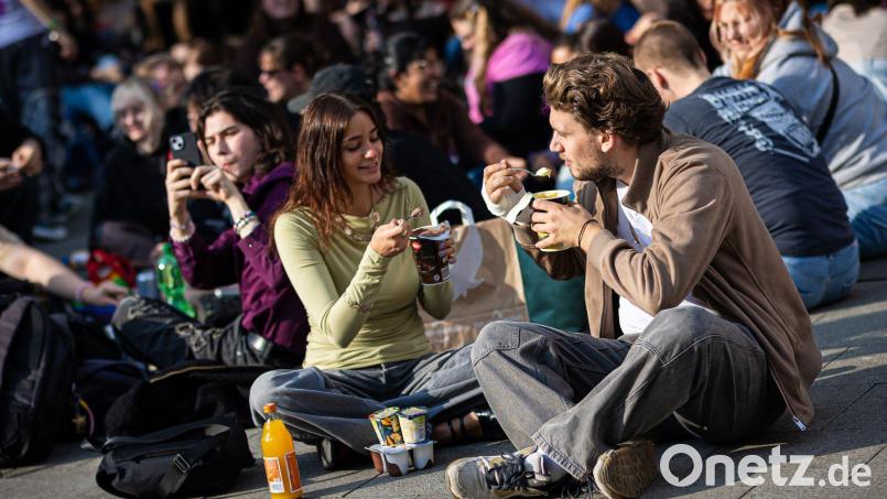 Zahlreiche Menschen treffen sich am Küchengarten, einem Platz in Hannover, um Pudding mit Gabeln zu essen. Bild: Moritz Frankenberg/dpa