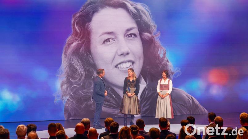 Die Biathletinnen Franziska Preuß und Magdalena Neuner (hier mir Moderator Markus Othmer vor einem Bild von Laura Dahlmeier) haben bei der Verleihung des Bayerischen Sportpreises ihrer gestorbenen Kollegin Dahlmeier gedacht. Bild: Alexandra BEIER/BayStMI/dpa