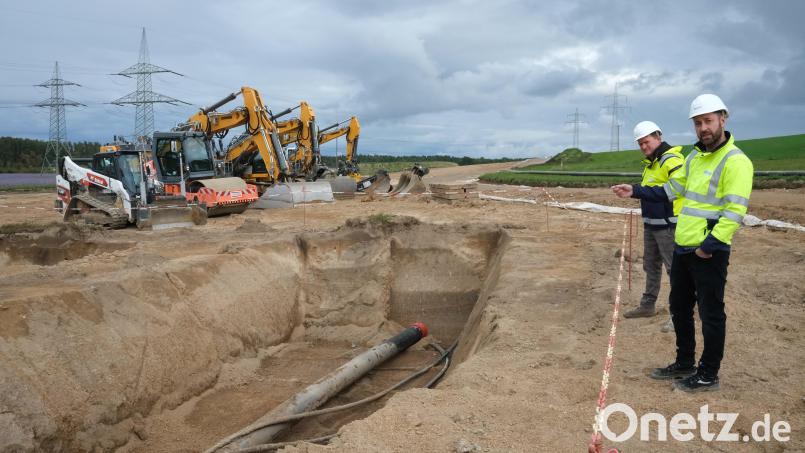 Mit schwerem Gerät werden 1,80 Meter tiefe Schneisen gegraben. Die TenneT-Vertreter Johannes Prechtl und Markus Lieberknecht (von rechts) erläuterten an der Baustelle bei Nittenau die Verlegung der Schutzrohre, in die später die Stromleitungen eingezogen werden. Bild: Hirsch