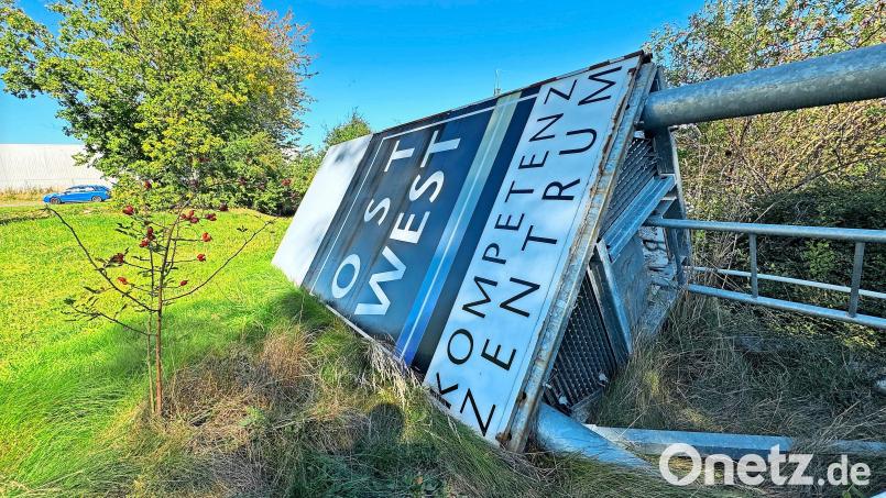 Die große Hinweistafel auf das Ost-West-Kompetenzzentrum liegt samt Masten auf dem Rasen. Bild: Matthias Bäumler