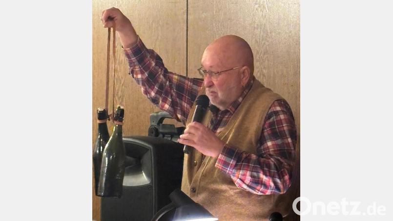 Wie Literflaschen Bier um den Hals gehängt und zum Arbeitsplatz getragen wurden, demonstriert Sepp Lösch bei seiner Lesung über die Geschichte der Maxhütte. Bild: Erhard Nitzbon