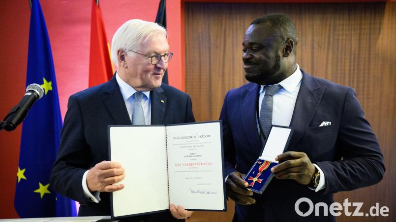 Der frühere Fußball-Nationalspieler Gerald Asamoah (r) erhält von Bundespräsident Frank-Walter Steinmeier das Bundesverdienstkreuz. Bild: Bernd von Jutrczenka/dpa