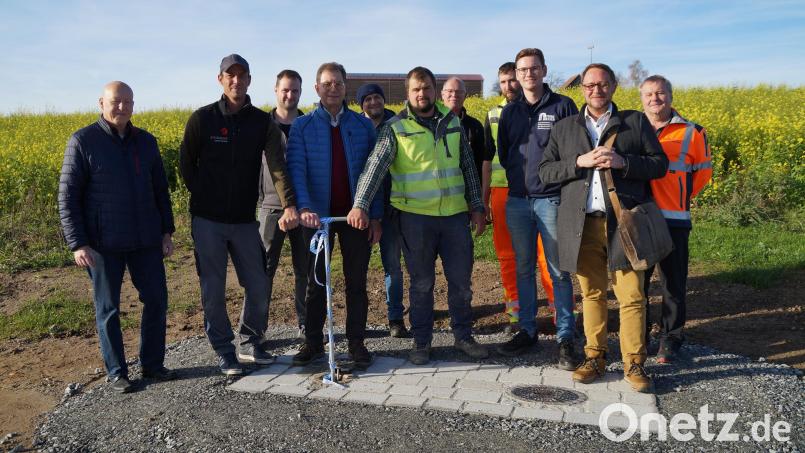 Der Vorsitzende des Zweckverbands zur Wasserversorgung der Nord-Ost-Gruppe, Klaus Zeiser (Vierter von links), freut sich zusammen mit den Bauherren Anton Steininger (links) und Siegfried Wagner (Fünfter von rechts) sowie Wolfgang Vetterl (Zweiter von rechts) und den Mitarbeitern über die erfolgreiche Sanierung der Wasserleitung parallel zur Staatsstraße. Im Hintergrund der Hochbehälter Pissau. Bild: wel