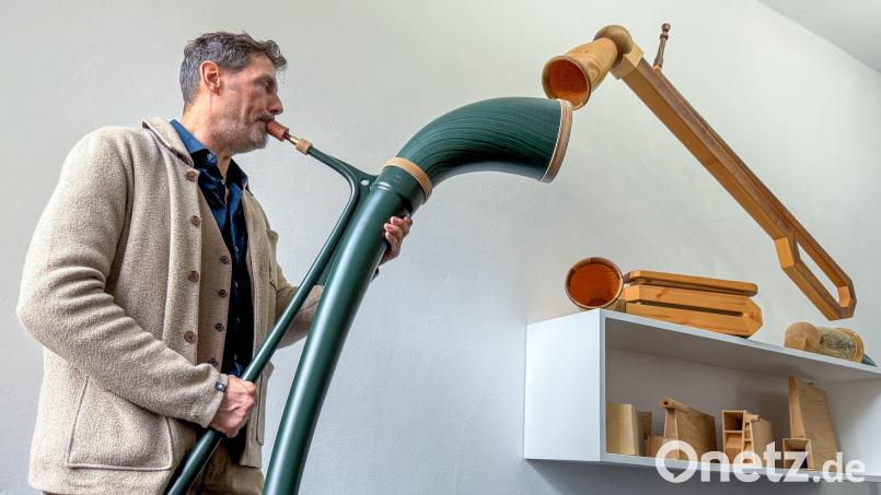 Instrumentenbauer Robert Vogel mit seiner neuesten Erfindung, der Mamba: Ein Exemplar des Plastik-Alphorns hat er jetzt dem Luftmuseum Amberg geschenkt. Dort gibt es auch schon die Vorgängermodelle aus Holz. Bild: Petra Hartl