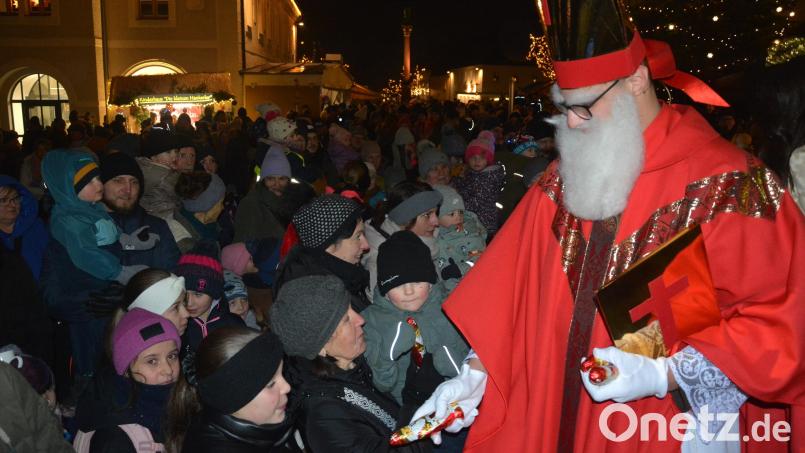 Sankt Nikolaus (von den Pfadfindern) verteilt auf dem Stufen zum Rathaus Schoko-Nikoläuse an die Kinder. Bild: jr