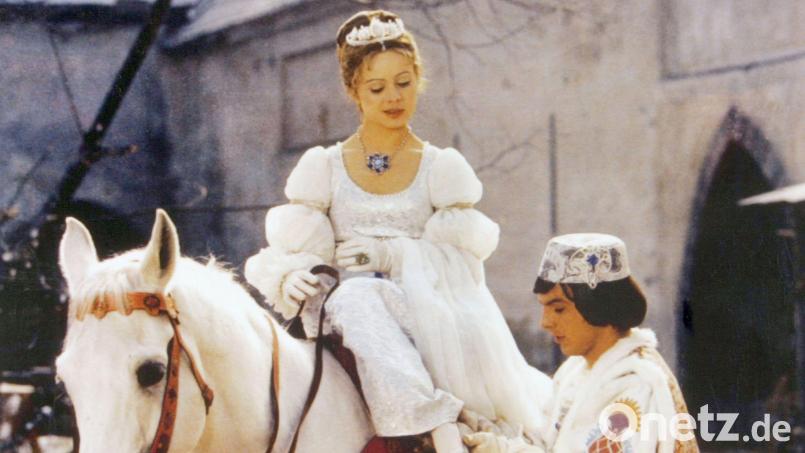 Der Prinz (Pavel Trávnícek) passt Aschenbrödel (Libuse Safránková) den verlorenen Schuh an. (Filmszene) Bild: Degeto/WDR/dpa