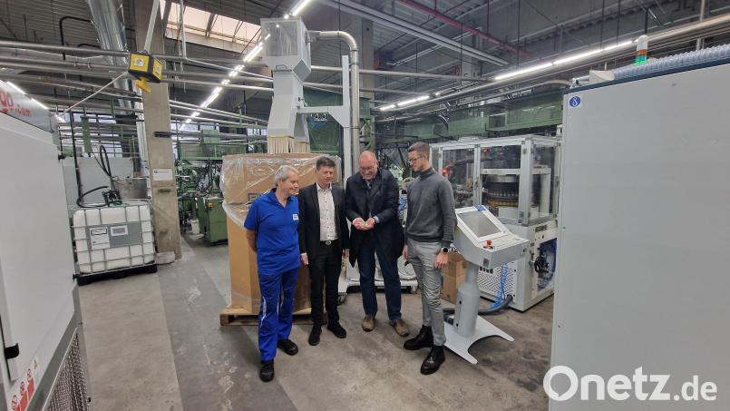 André Rauch (Zweiter von links) und Marius Rauch (rechts) von der Gesellschafterfamilie mit Geschäftsführer Rainer Gräf (Zweiter von rechts) und Mitarbeiter Udo Müller an der neuen Maschine. Pro Minute zieht sie bis zu 2800 Verschlusskappen aus Aluminium. Bild: pr