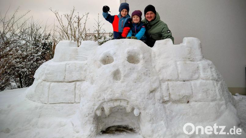 Peter Kick (rechts) hat mit seinen Kindern Marlene (Mitte) und Raphael (links) den Schädel von "Castle Grayskull" aus Schnee gebaut– der bekannten Festung aus der Zeichentrickserie "He-Man – Im Tal der Macht". Bild: Peter Kick