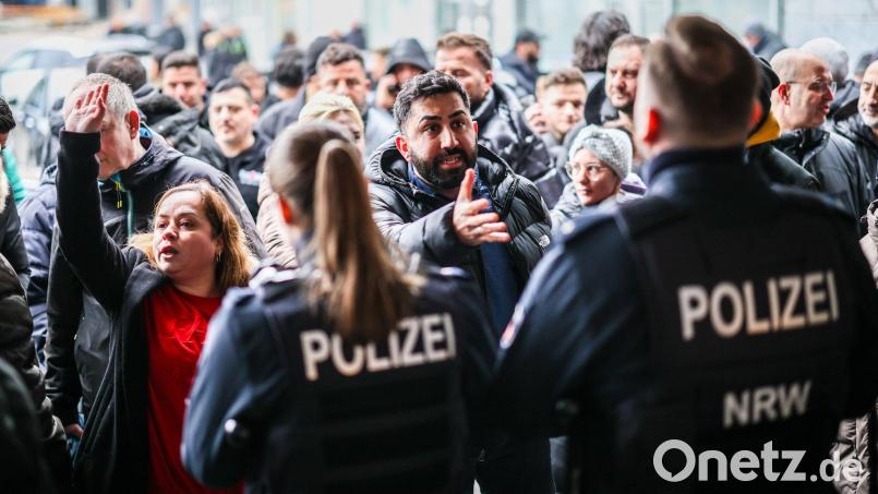 Aufgebrachte Kunden diskutieren vor der Sparkassenfiliale mit Polizeibeamten (Archivfoto) Bild: Christoph Reichwein/dpa