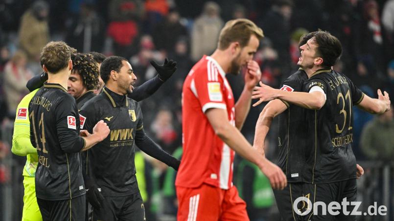 Die Spieler des FC Augsburg jubeln nach Spielende. Bayerns Harry Kane (rotes Trikot) ist frustriert. Die Münchener verloren mit 1:2. Bild: Peter Kneffel/dpa