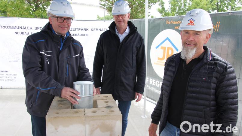 Bürgermeister Roman Schäffler (links) setzt die Blechdose in das Mauerwerk ein. Bei diesem Akt mit dabei waren auch Johannes Fischer vom Planungsbüro Fischer (Mitte) aus Marktredwitz sowie Josef Reger von der Baufirma Reger-Bau aus Vohenstrauß. Bild: kro