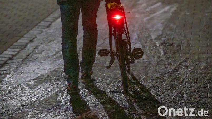 Ein Mann schiebt sein Fahrrad auf einer vereisten Straße. Bild: Armin Weigel/dpa