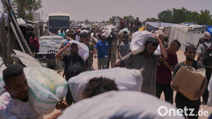 Palästinenser tragen Taschen mit Lebensmitteln und humanitären Hilfspaketen, die von der Gaza Humanitarian Foundation, einer von den USA unterstützten Organisation, geliefert wurden. Bild: Abdel Kareem Hana/dpa