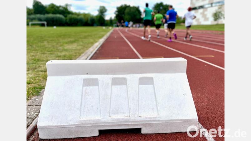 Auf der inneren Bahn der Realschul-Sportanlage in Weiden stehen weiße Kunststoffblöcke. Sie decken Schäden in der Tartanbahn ab und sollen verhindern, dass jemand in die Löcher tritt. Bild: Gabi Schönberger