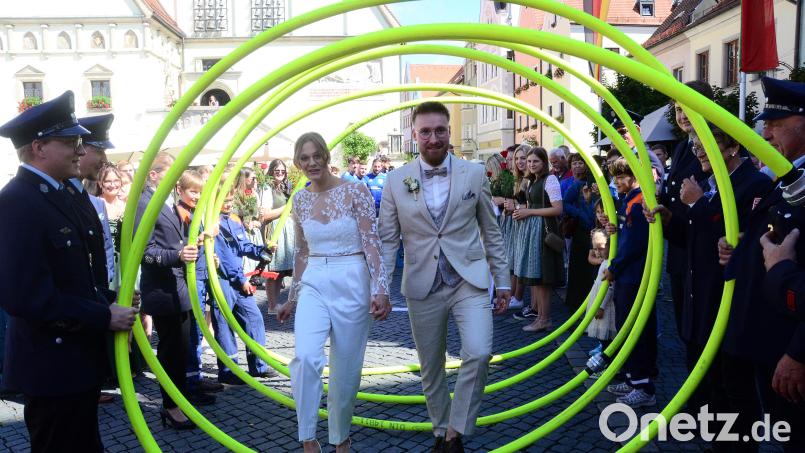 Julia und Bastian Strehl schreiten gemeinsam durch ein Spalier aus Feuerwehrschläuchen. Bild: Kunz