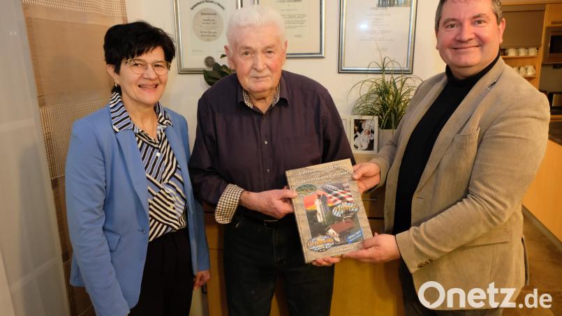 Mit dem historischen Band über den Truppenübungsplatz Grafenwöhr und die Ereignisse rund um das Kriegsende im Bereich der Region gratulierten dem Jubilar (Mitte) Bürgermeister Dr. Alexander Goller und zweite Bürgermeisterin Irmi Bauer. Bild: do