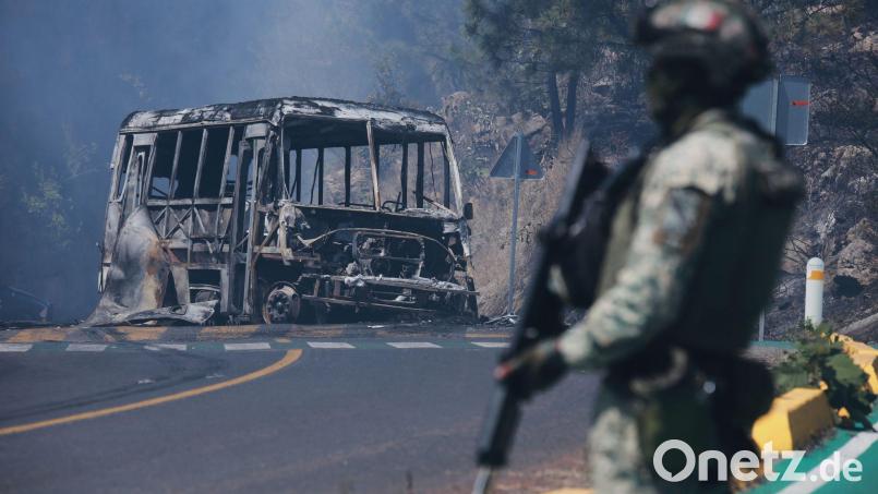 Ein Soldat steht in Mexiko - einem der drei Ausrichterländer der Fußball-WM im Sommer - neben einem ausgebrannten Bus. Bild: Armando Solis/AP/dpa