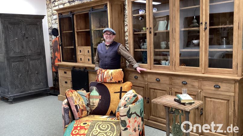 Der Geschäftsinhaber vor seinen Schränken. Links ein alter original indischer Schrank und zwei verschiedene Vitrinenschränke aus recyceltem, indonesischem Teakholz in geschliffener und gebürsteter Ausführung (links/rechts). Der Schaukelsessel ist von einem spanischen Partner, der nur ein Prozent Abfall produziert. Das Mittelelement des Beistelltisches ist von einem ehemaligen Metallgeländer Bild: Monika Ziegeler