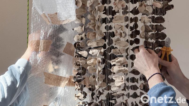 Museumsmitarbeiter entwirren vorsichtig die an Nylonschnüren aufgehängten Tonscherben – ein Objekt aus der Serie "Boundless Vases" der nigerianischen Künstlerin Ngozi-Omeje Ezema. Die offizielle Einweihung im Keramik-Museum Weiden steht noch aus. Bild: Gabi Schönberger