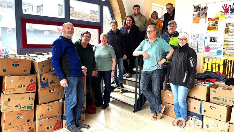 Ein Teil der mit Büchern gefüllten 60 Bananenkisten steht im Eingangsbereich der Kindertagesstätte St. Vitus zum Abholen bereit. Die Helferinnen und Helfer der Ausräumaktion um Büchereileiterin Angelika Fromm (Dritte von links) packten die Bücher zusammen. Bild: Norbert Weis