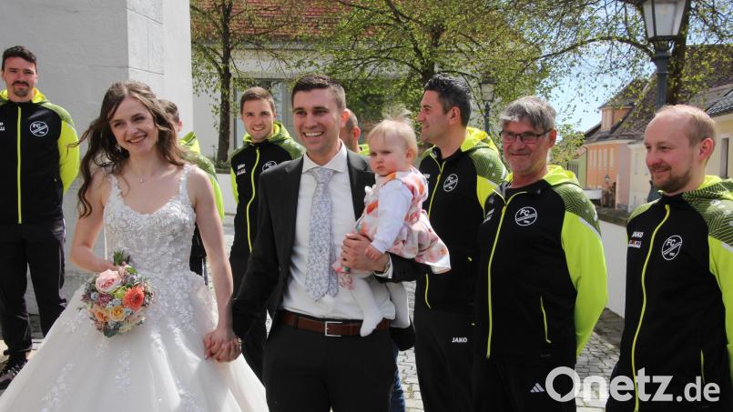 Freudestrahlend verlassen Laura und Johannes Klinger mit ihrem gemeinsamen Töchterchen die Stadtpfarrkirche, vorbei am Ehrenspalier des FC Tirschenreuth. Bild: Konrad Rosner