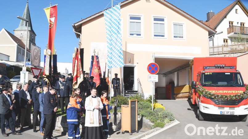 Kaplan Marvin Schwedler, umrahmt von den Fahnen der teilnehmenden Feuerwehren, bei der Segnung des neuen Einsatzfahrzeuges der FFW Aschach. Bild: sche