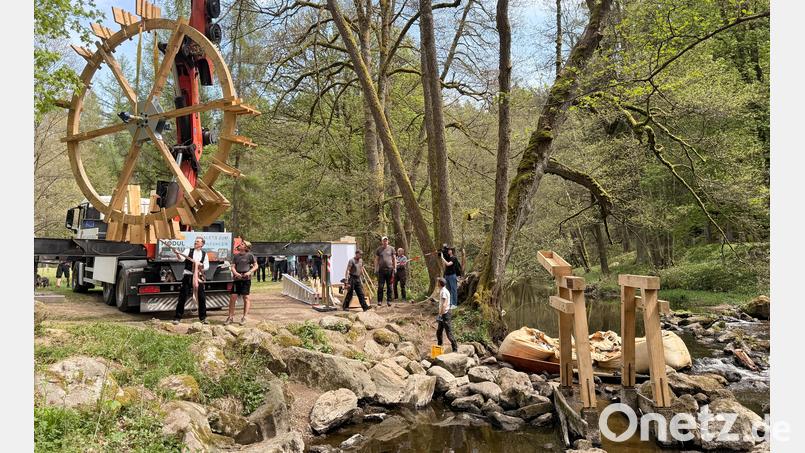 Das historische Wasserschöpfrad ist wieder an seinem angestammten Platz im Waldnaabtal. Von einem Lastwagen aus schwebte die rund zweieinhalb Tonnen schwere Konstruktion aus Eichenholz mit einem Durchmesser von fünf Metern durch die Luft. Sicher befestigt an einem Kran, den Zimmerermeister Antonio Schatzberger (am Lastwagen, rechts) bediente. Sein Vater Anton Schatzberger (links daneben) ist ebenfalls Zimmerermeister und packte mit an. Bild: Gabi Schönberger