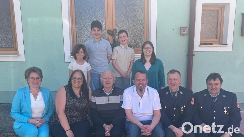 Jubilar Johann Wutz (vorne, Dritter von links) zwischen seinen beiden Kindern Despina und Joachim, Bürgermeisterin Sonja Meier und den Feuerwehrkameraden Markus Schöberl und Otto Frischmann. Dahinter seine Enkel Eva, Max, Leo und Anna (von links). Bild: Manuela Wutz
