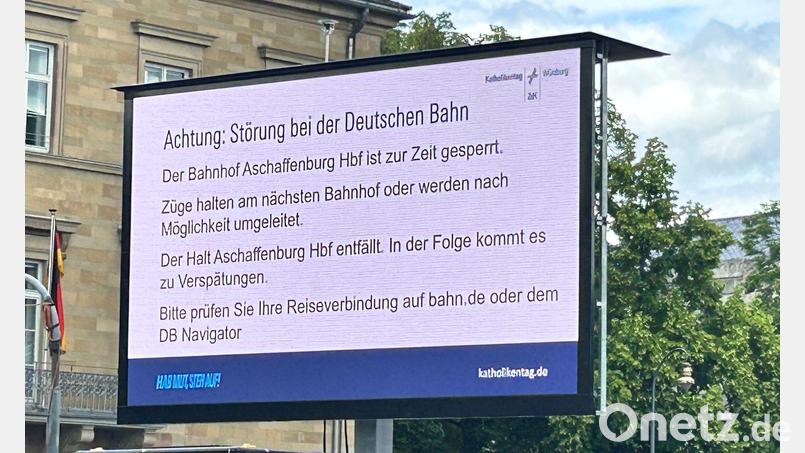 Ein Hinweis macht die Besucher des Katholikentags in Würzburg auf die wenig später aufgehobene Sperrung des Bahnhofs in Aschaffenburg aufmerksam. Bild: Angelika Resenhoeft/dpa